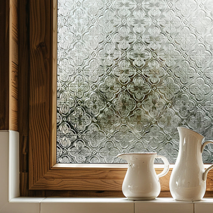 Embossed etched-glass window film on a timber-framed window, a repeating quatrefoil relief diffusing the view outside.