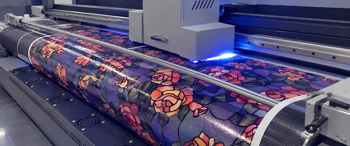 A wide-format printer laying an original rose stained-glass pattern onto a roll of decorative window film on the FancyFix production line.
