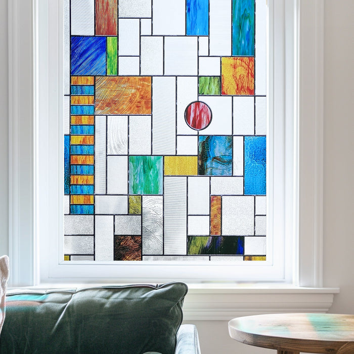 Modern stained glass window film in an irregular colour-block leaded grid of blue, orange and green on a window