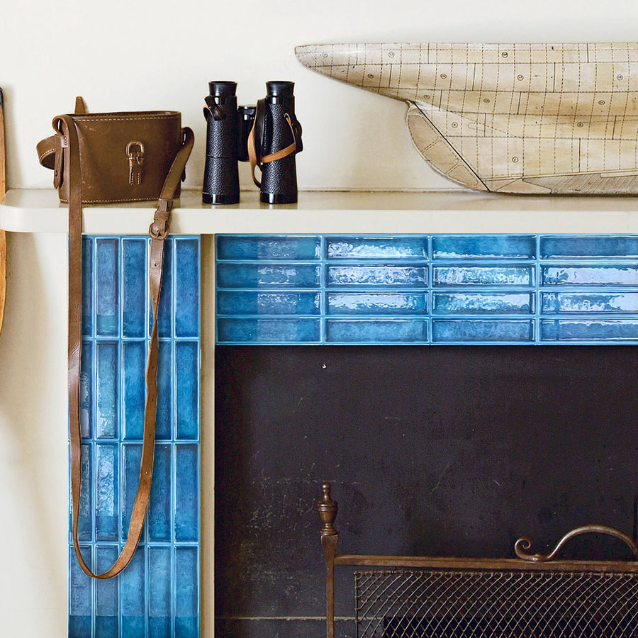 Blue glazed tile-effect wall covering framing a fireplace with a display shelf above
