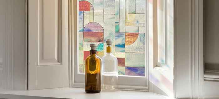 Geometric decorative window film in blocks of colour on a window, casting tinted light onto the sill.