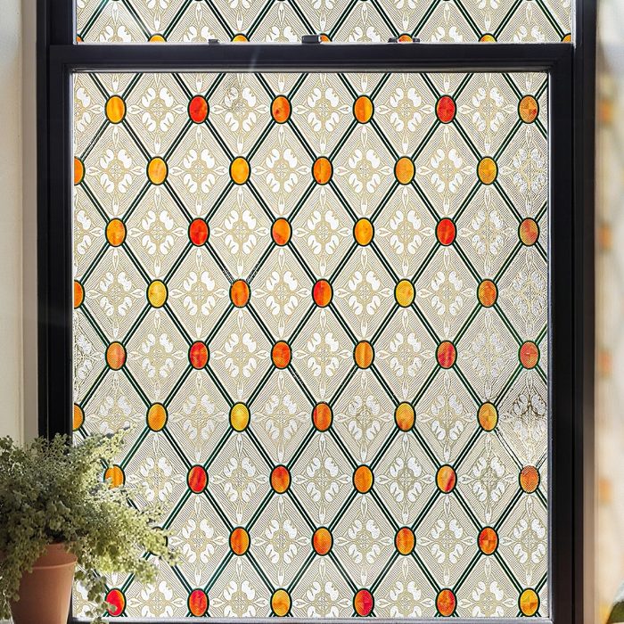 Gothic stained glass window film in a black window frame, diamond lattice with red and amber jewels