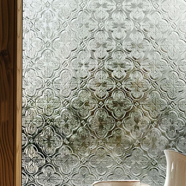 Vintage embossed window film on a timber-framed window, damask relief catching side light